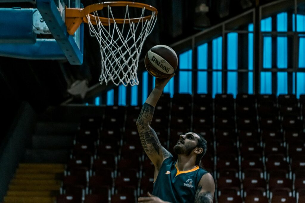 A focused basketball player scores a point in a dimly lit indoor court, showcasing athletic talent.